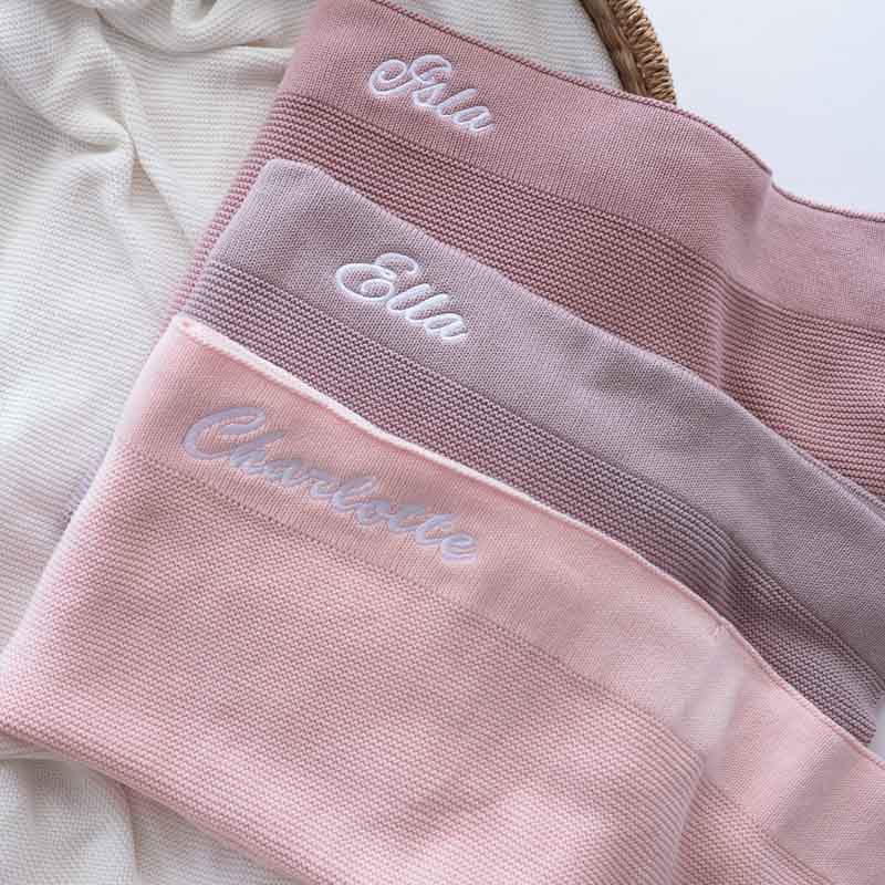 Three pink and lilac personalised baby blankets with embroidered names Isla, Ella, and Charlotte.