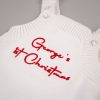White 1st Christmas Newborn Romper Close up of white knitted newborn romper chest with red embroidered personalised 1st Christmas script text and snap button shoulders.
