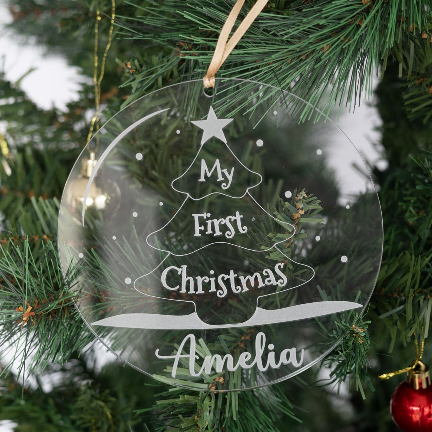 Personalised clear acrylic Christmas Disc engraved with My First Christmas Amelia hanging on tree with tree design.
