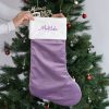 Personalised lilac velvet Christmas stocking with white cuff and Matilda embroidered in purple.