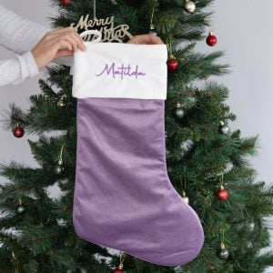 Personalised lilac velvet Christmas stocking with white cuff and Matilda embroidered in purple.