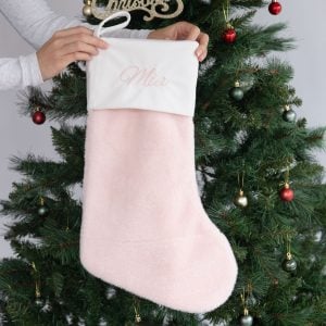 Personalised pink faux fur Christmas stocking with white cuff and Mia embroidered in pink.