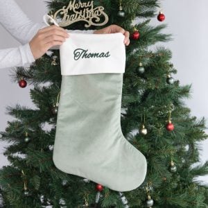 Personalised sage green velvet Christmas stocking with white cuff and Thomas embroidered in green.