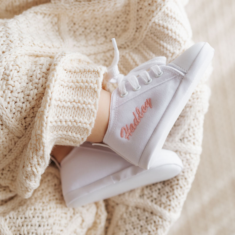 White personalised baby shoes on cream diamond knit blanket.