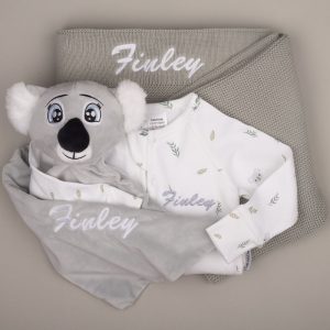 Koala-print baby onesie, grey koala comforter, and sage knitted blanket, all personalised with the name ‘Finley.