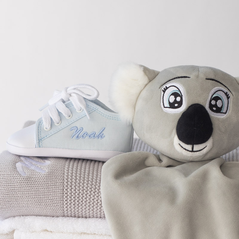 Personalised blue baby shoe with “Noah” and koala comforter on knitted blankets.