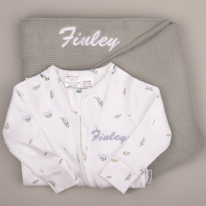 Green Sage Blanket Koala Onesie Finley White koala-print baby onesie with name ‘Finley,’ displayed on a sage green knitted blanket with matching embroidery.