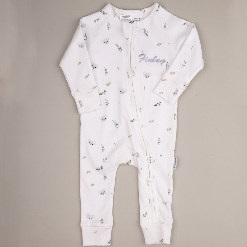 Koala Baby Onesie Finley White baby onesie with koala and leaf pattern, front zipper, and embroidered name ‘Finley.’