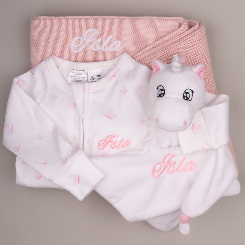 Pink Baby Blanket Unicorn Comforter Butterflies Onesie Soft pink-and-white baby gift set with personalized blanket, onesie, and unicorn comforter embroidered with the name “Isla.”