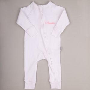 White baby onesie with front zipper and pink embroidered name ‘Amelia.’