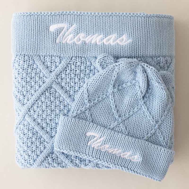 Light blue knitted baby blanket and beanie with embroidered name Thomas.