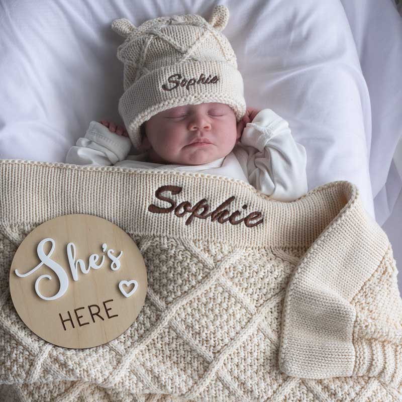 Cream baby blanket and beanie set styled for newborn photo.