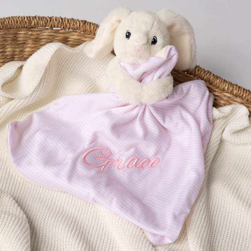 White bunny comforter with personalised pink blanket on knitted throw.