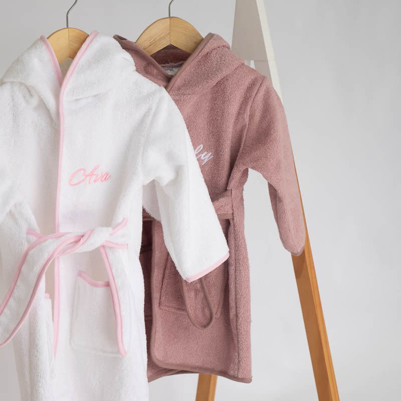 Two personalised hooded bunny baby robes in soft neutral and pink tones.