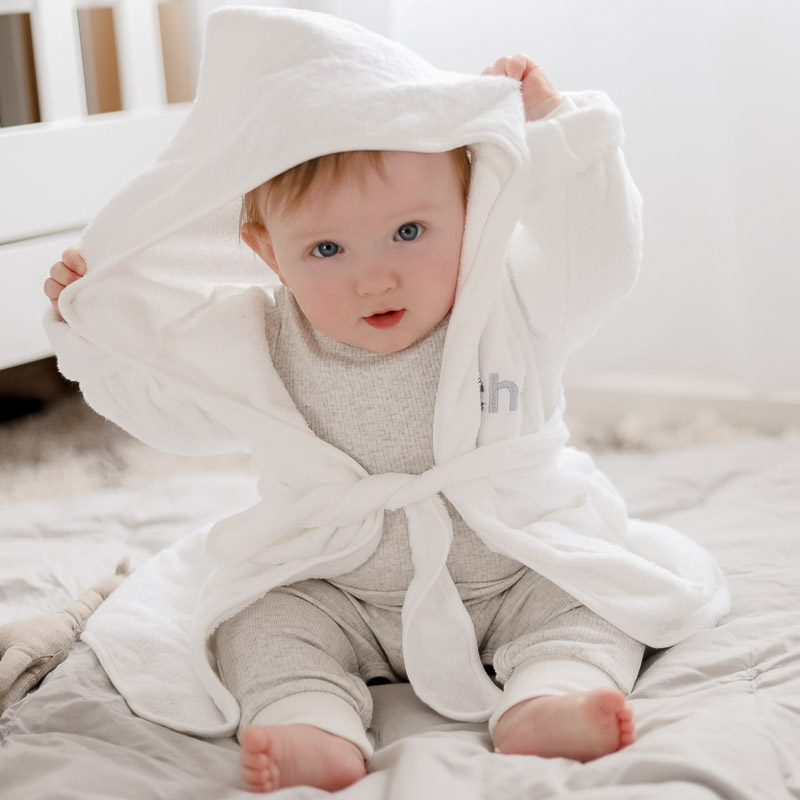Baby wearing personalised white hooded bath robe.