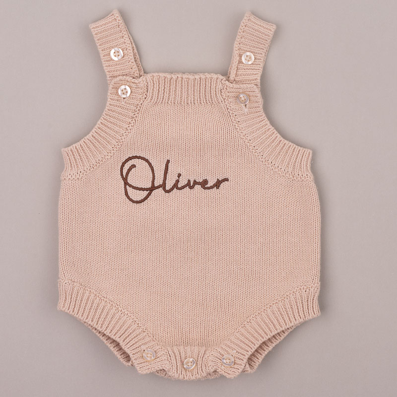 Beige knitted baby romper embroidered “Oliver” in brown script.