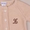 Beige Knitted Cardigan Close Brown Initial L Close-up of beige knitted baby cardigan with buttons and brown embroidered letter “L” on chest.