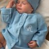Blue Baby Cardigan Initial R Close Up Sleeping newborn wearing a personalised blue knitted cardigan and matching beanie with an embroidered initial.