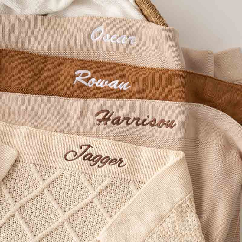 Neutral personalised knitted baby blankets with embroidered names.