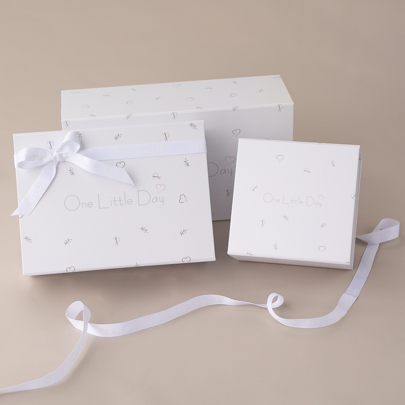 White One Little Day baby gift boxes with ribbon ties.