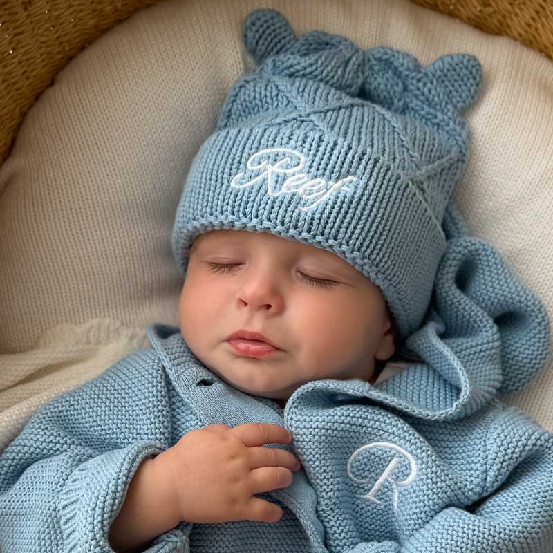 Sleeping baby wearing blue personalised knitted beanie.