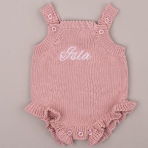 Blush pink frill knitted baby romper embroidered “Isla” in white script.