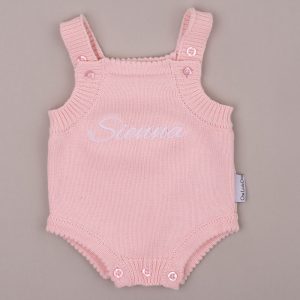 Pink knitted baby romper with scalloped edge embroidered “Sienna” in white script.
