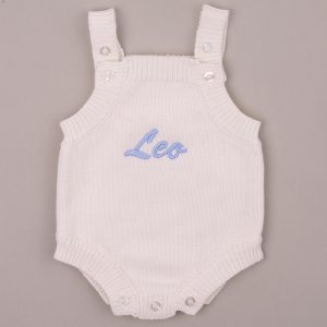 White knitted baby romper embroidered “Leo” in blue script.