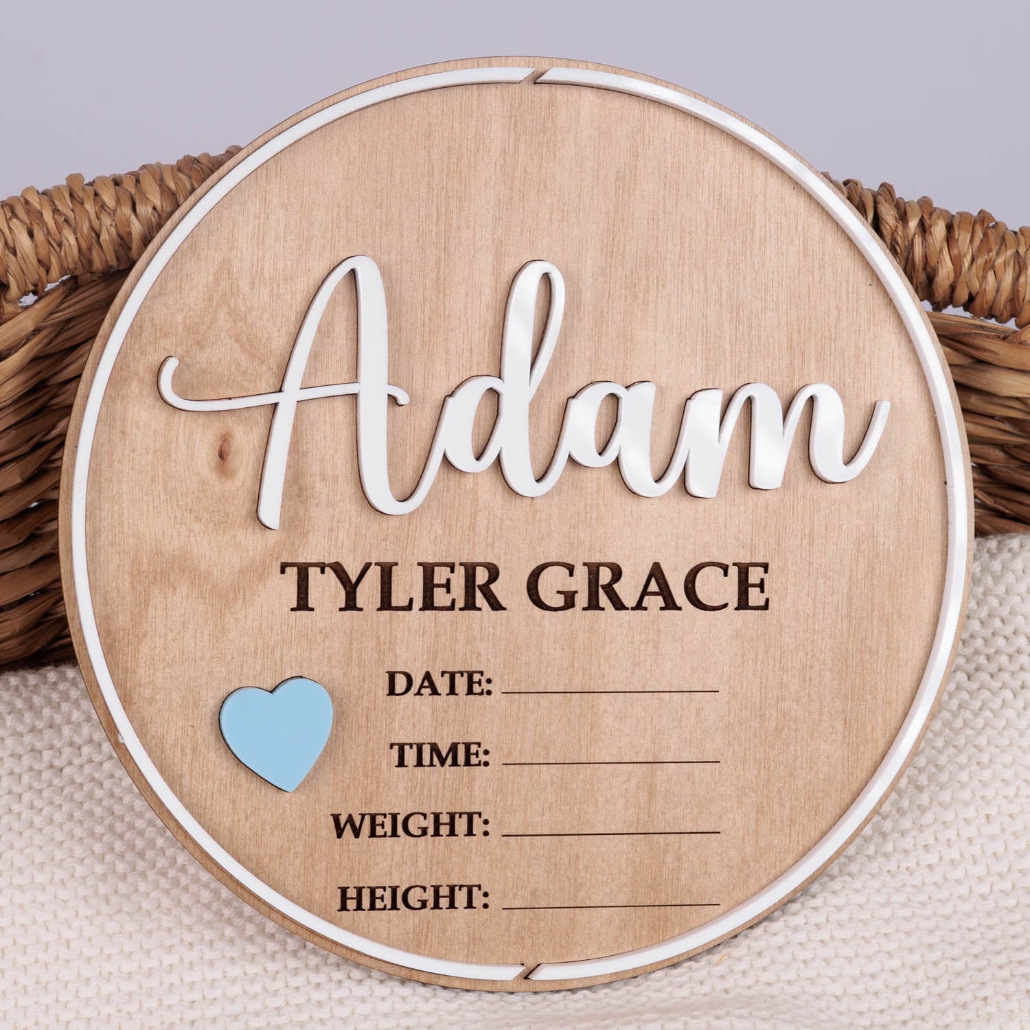 Personalised round wooden nursery plaque with Adam in white and Tyler Grace engraved with blue heart and birth detail fields