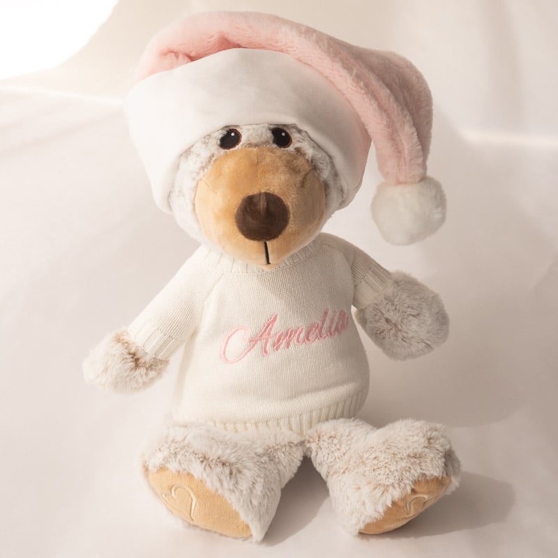 A personalised teddy & jumper wearing a pink santa hat.