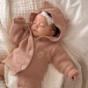 A baby sleeping in a Blush Pink Hooded Knitted Baby Cardigan embroidered with the letter O.