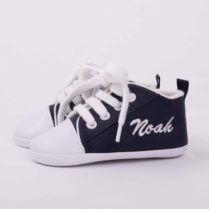 Personalised navy blue baby shoes with Noah embroidered in white.