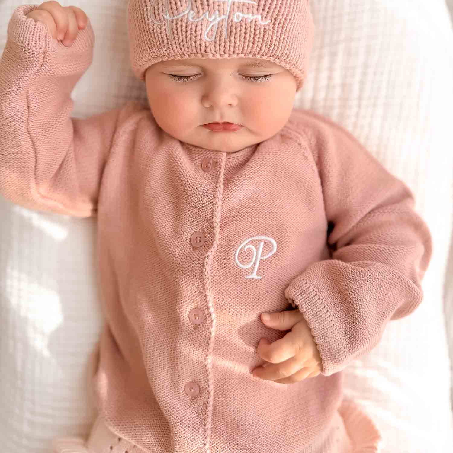 Sleepy Baby Resiting In A Blush Pink Caridgan Initial.