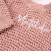 Blush Pink Long Sleeve Baby Romper Close Up Close-up of personalised blush pink chunky knit baby romper showing white embroidered name and ribbed sleeve detail