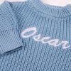 Long Sleeve Blue Baby Romper Close Up Oscar Close-up of personalised blue chunky knit baby romper showing white embroidered name and ribbed sleeve detail