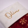 Burgundy & Gold Baby Christmas Stocking Close Up Close-up of personalised burgundy and gold snowflake velvet baby Christmas stocking with gold Oliver embroidery on white cuff