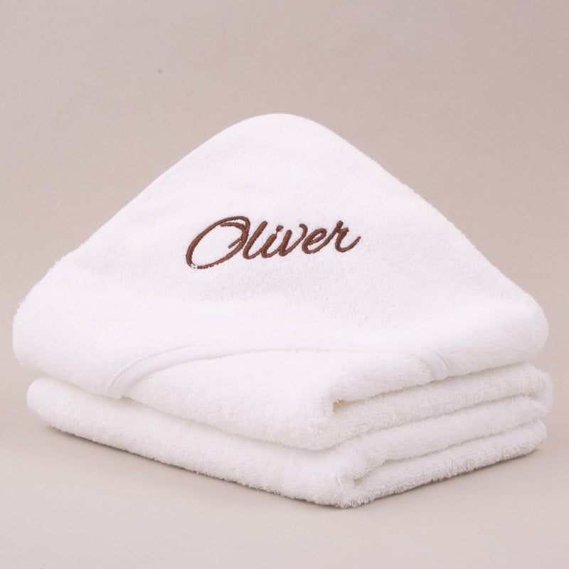 Folded personalised white hooded baby towel embroidered with the name Oliver in brown script.