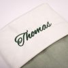 Sage Green Baby Christmas Stocking Close Up Close-up of personalised sage green velvet baby Christmas stocking with dark green Thomas embroidery on white cuff