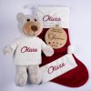 4 Piece Personalised Bear & Disc Christmas Baby Gift Olivia Four piece personalised Christmas baby gift set including grey plush teddy bear in white knitted jumper, burgundy velvet stocking, Santa hat with white cuff and wooden My First Christmas disc all with burgundy embroidered script name.