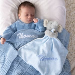 Sleeping newborn baby boy named Thomas wearing a personalised blue knitted romper lying on a blue diamond blanket with a personalised elephant comforter.